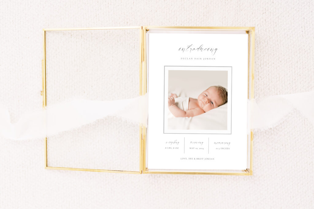 Image of a Birth Announcement in a glass box with ribbon by Courtney Grant Photography